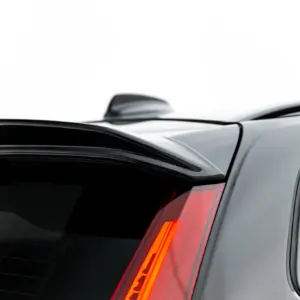 Close-up of the rear end of a silver SUV, showing a dark rear window, red taillight, and a small spoiler along the top edge of the tailgate.