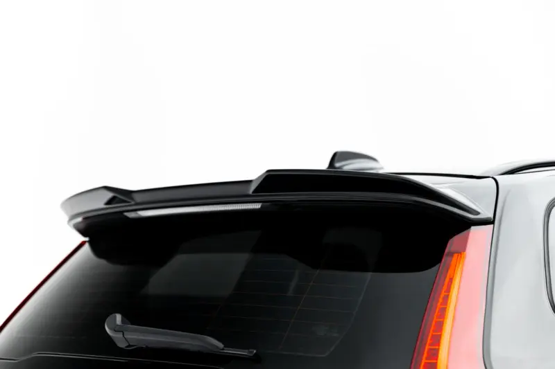 Close-up of the back of a white SUV showing a rear spoiler, curved tail light, and rear wiper on a dark rear window.