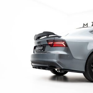 Rear-right view of a silver Audi with the trunk open and red taillights illuminated in a bright showroom; partial wall text visible in the background (MAX...).