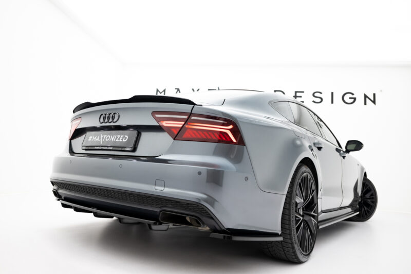 Rear three-quarter view of a silver Audi sedan in a bright white studio, showing taillights and large alloy wheels.