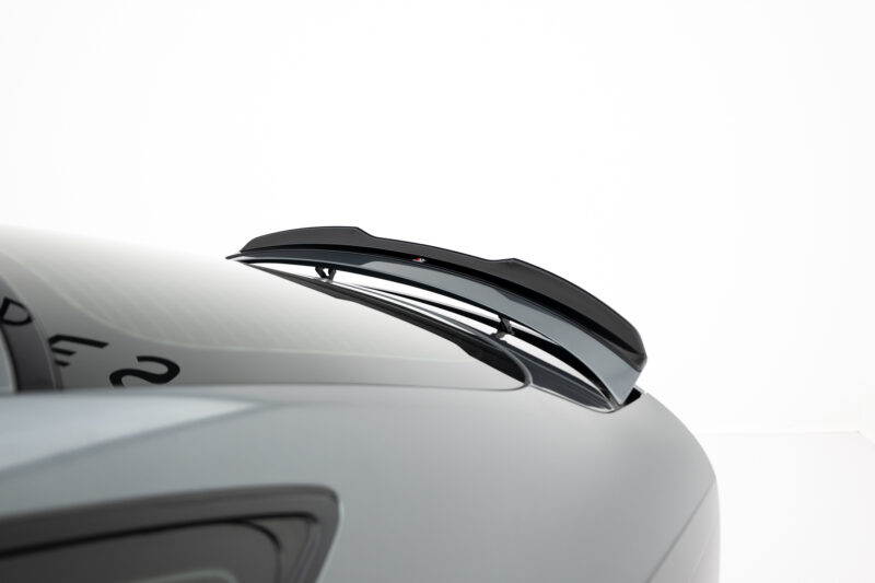 Close-up of a car roof with a glossy black aerodynamic spoiler, viewed from the side against a white background.