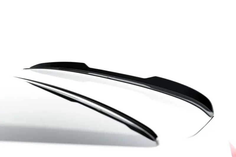 Close-up of glossy black windshield wipers resting along the curved windshield of a white car.