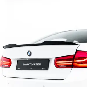 White BMW rear view showing spoiler, taillights, and a black license plate area with '#MAXTONIZED' text.