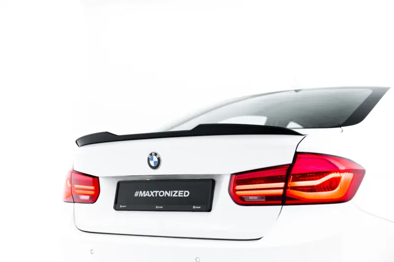 White BMW rear view showing spoiler, taillights, and a black license plate area with '#MAXTONIZED' text.