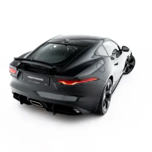 Rear three-quarter view of a dark gray Jaguar F-Type sports car against a white background, highlighting the sleek curves and taillights.