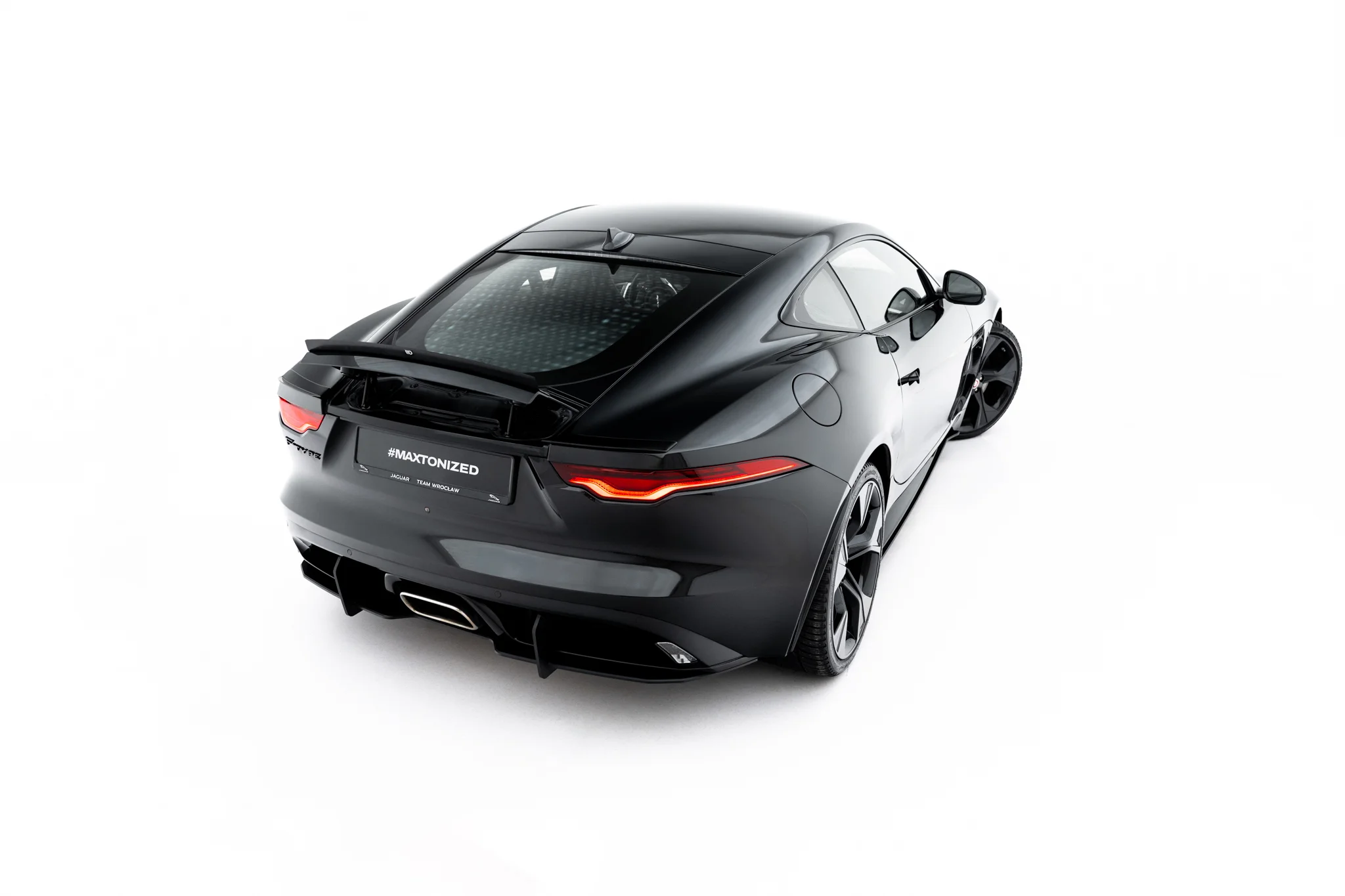 pol_po_Spoiler-Cap-Jaguar-F-Type-X152-Facelift-2-23971_1webp - OPSHOLDERS Rear three-quarter view of a dark gray Jaguar F-Type sports car against a white background, highlighting the sleek curves and taillights.