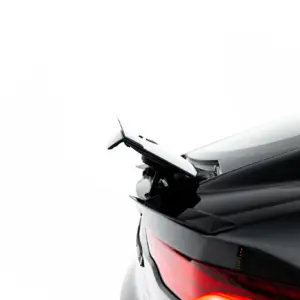 Close-up of the rear end of a white car, showing the red tail light and rear wiper against a white background.