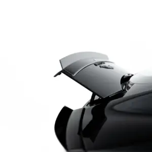 Close-up of a glossy black car with a rear spoiler against a white background, highlighting the aerodynamic spoiler.
