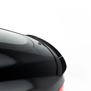 Close-up of the front corner of a black car, showing the glossy hood, windshield, and a wiper on a white background.