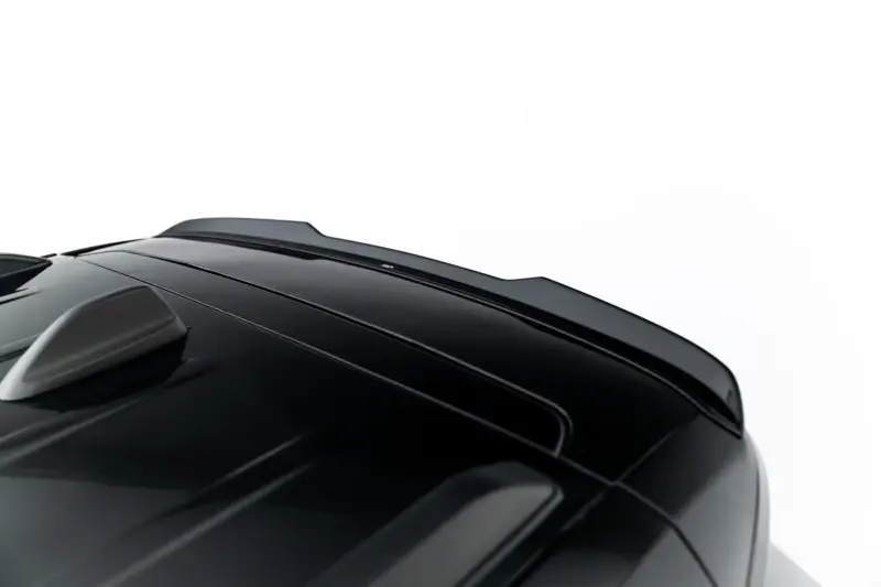Close-up of a glossy black car roof with sleek lines and a rear spoiler, viewed from a low angle