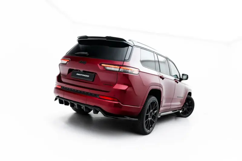 Rear three-quarter view of a red Jeep SUV in a studio, showing bold taillights and a black roof rack, with a dark license plate reading '#MAXTONIZED'.