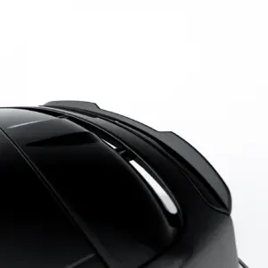Close-up of a glossy black car roof and windshield with reflections against a white background, highlighting sleek curves of the vehicle.