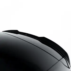 Close-up of a glossy black car windshield and roof edge against a white background.