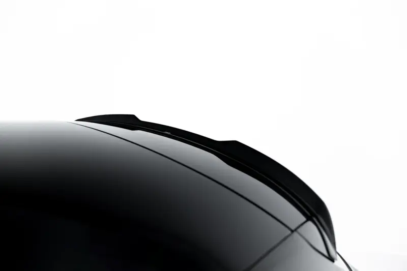 Close-up of a glossy black car windshield and roof edge against a white background.