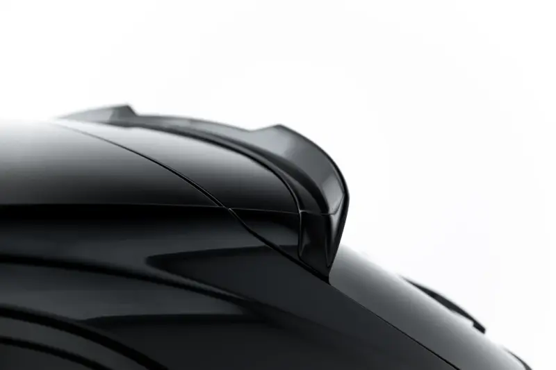 Close-up of a shiny black car body with curved panels against a white background, highlighting reflections and contours.