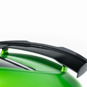 Close-up of a glossy black aerodynamic part on a bright lime-green surface, highlighting sleek curves and reflections.