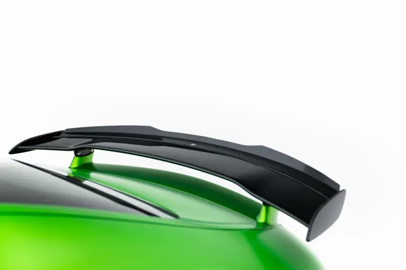 pol_po_Spoiler-Cap-Mercedes-AMG-GT-R-C190-Facelift-23891_5webp - OPSHOLDERS Close-up of a glossy black aerodynamic part on a bright lime-green surface, highlighting sleek curves and reflections.