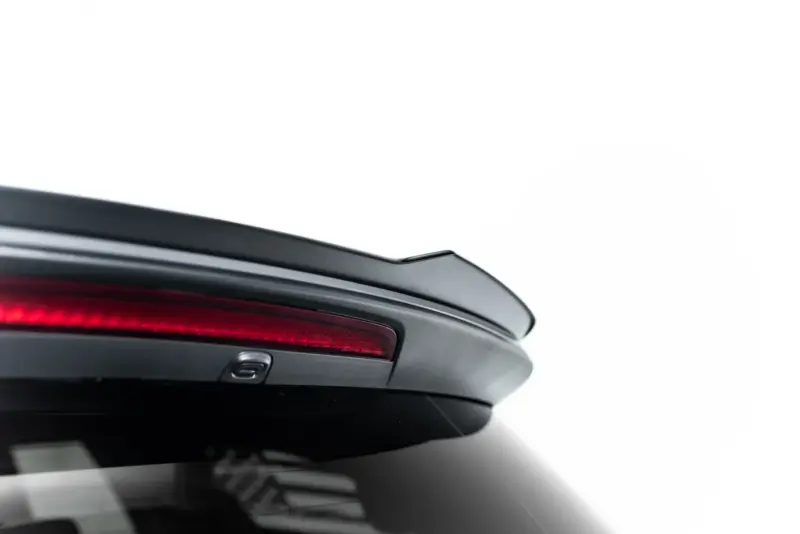 Close-up of a car's rear end showing a red taillight and the edge of the trunk against a white background.