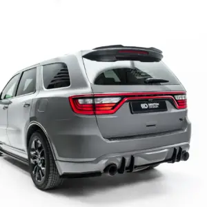 Rear angled view of a silver SUV with an aftermarket roof spoiler and quad exhausts, Maxon Design plate visible at the back edge.