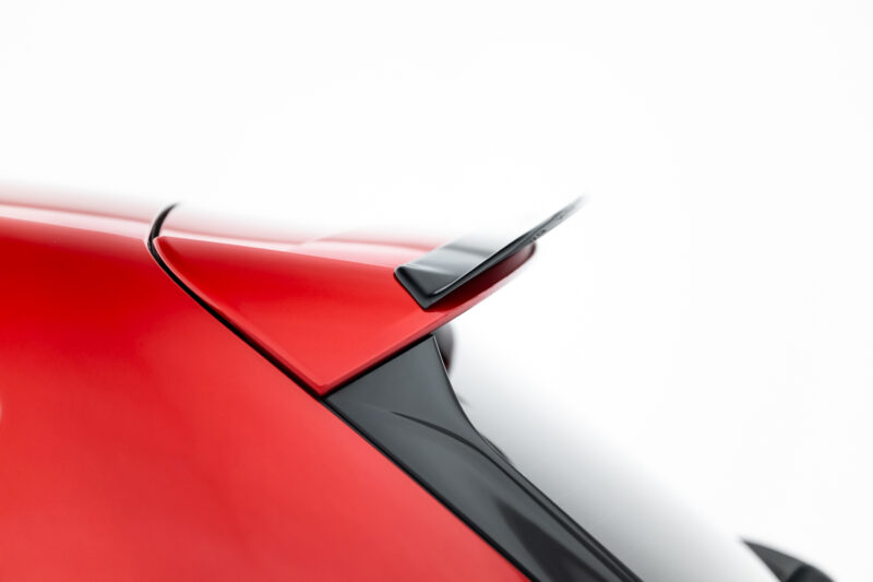 Close-up of a glossy red car body with a black trailing edge and spoiler detail.
