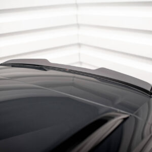 Close-up of a dark car hood with windshield wipers visible against a bright, striped background (garage).﻿