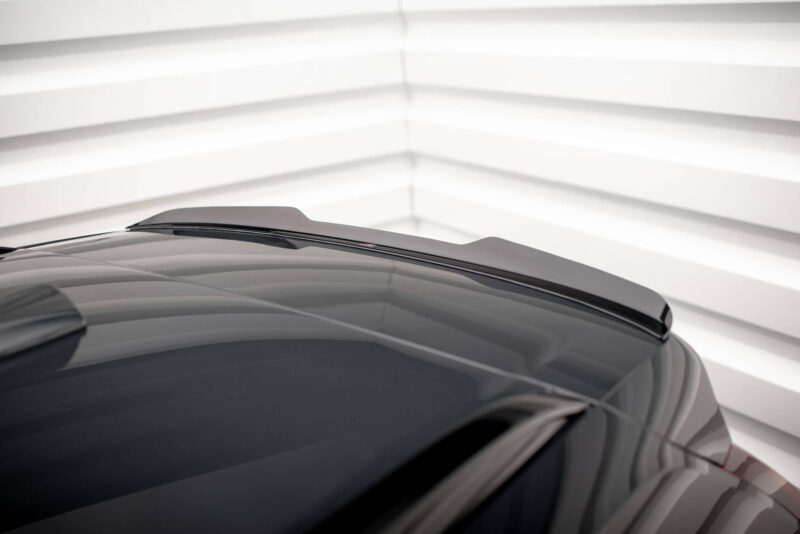 Close-up of a dark car hood with windshield wipers visible against a bright, striped background (garage).﻿