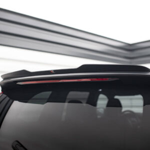 Rear view of a dark SUV showing a large spoiler on the tailgate in a bright showroom.
