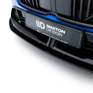 Close-up of a blue car's front bumper with a branded license plate reading 'Maxton Design' and small M stripes logo nearby