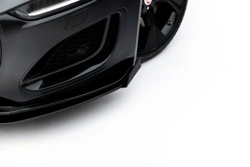 pol_po_Street-Pro-Front-Splitter-Flaps-Jaguar-F-Type-X152-Facelift-2-23975_2webp - OPSHOLDERS Close-up of a glossy black car's front bumper and honeycomb grille.