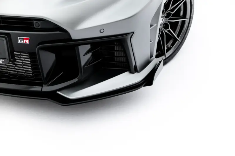 Close-up of a gray sports car’s front bumper with a black grille and GR badge visible on the left.