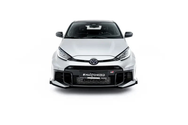 Front view of a silver Toyota car with a black grille, warning lights, and prominent bumper against a white background (vehicle centered).