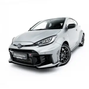 Front-left angled view of a white Toyota GR sports hatch with black grille and large alloy wheels, showcasing its aggressive styling.