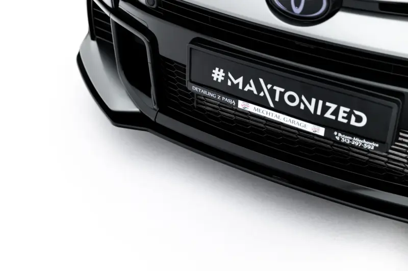 Close-up of the front bumper of a black car with a plate reading '#MAXTONIZED' and detailing sponsor text.