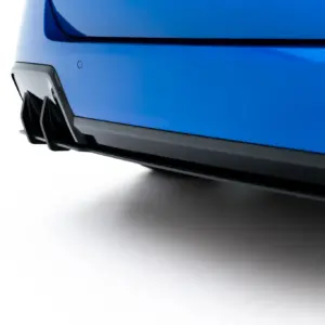 Close-up of a blue car's front bumper and lower grille against a white backdrop, highlighting the vehicle's design detail near the fog light area.