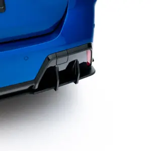 Close-up of a blue car's rear end, showing the bumper, tail light, and a partial license plate against a white background.