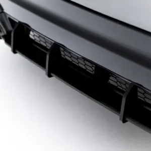 Close-up of a glossy black car front bumper featuring a hexagonal honeycomb grille.
