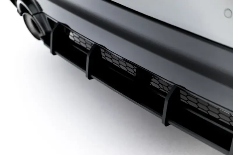 Close-up of a glossy black car front bumper featuring a hexagonal honeycomb grille.