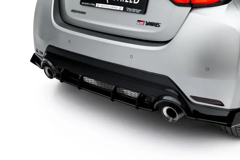 Close-up of the rear bumper of a silver car, showing exhaust pipes and bumper details.