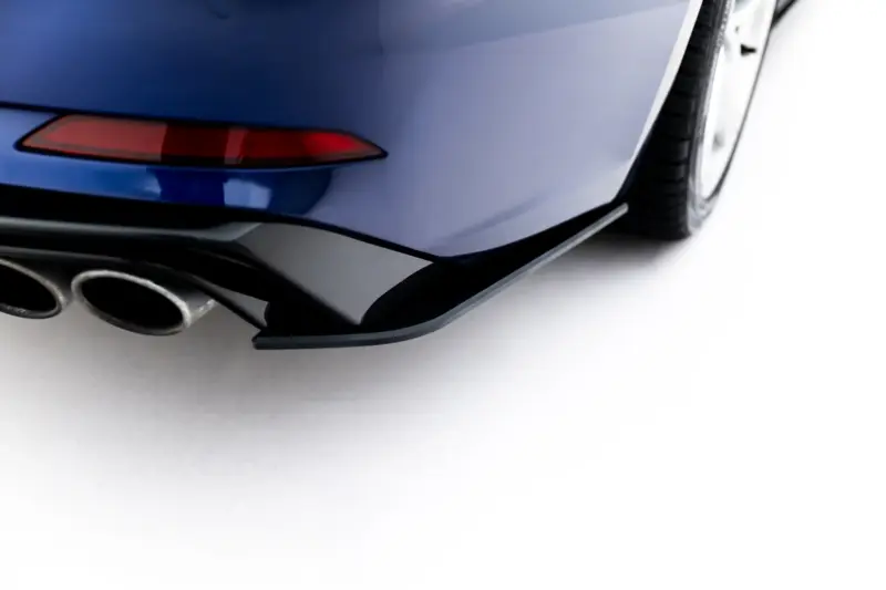 Close-up of the rear corner of a blue car, showing a red taillight, curved bumper, and dual exhaust tips.