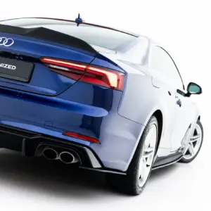 Rear three-quarter view of a blue Audi with taillights lit and a #MAXTONIZED plate on the trunk lid edge