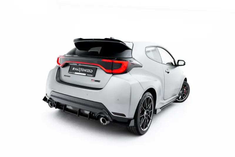 pol_po_Street-Pro-Rear-Side-Splitters-Flaps-Toyota-GR-Yaris-Mk4-Facelift-23793_2webp - OPSHOLDERS Rear three-quarter view of a white modern hatchback with a black roof spoiler and red taillights.