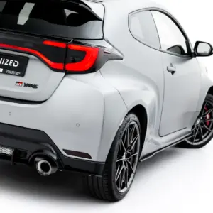 Rear view of a white GR Yaris showing a red tail light, rear bumper, and exposed exhaust with sporty alloy wheels; license plate reads '#MAXTONIZED'.