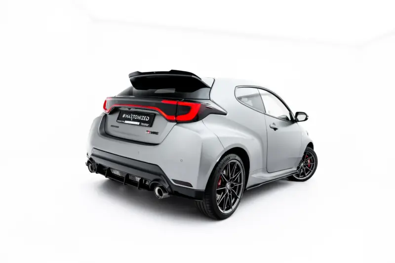 Rear three-quarter view of a silver sports hatchback with a black spoiler, red taillights, large wheels, and a license plate reading #MAJTONIZED against a white studio background