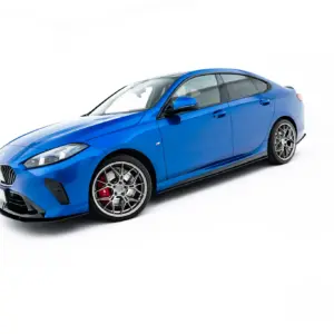 Three-quarter front view of a bright blue BMW-style sports coupe with large silver multi-spoke wheels and red brake calipers against a white studio background.