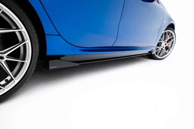 Close-up of a blue sports car's side with a prominent alloy wheel and brake calipers visible at the rear.