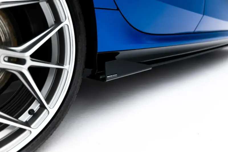 Close-up of a blue car showing its alloy wheel and lower body panel with a glossy finish.