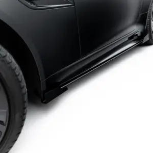 Close-up of a black car's side panel and wheel, highlighting the glossy finish and tire tread visible at the edge of the frame.
