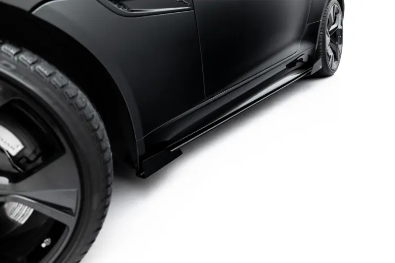 Close-up of a black car's side panel and wheel, highlighting the glossy finish and tire tread visible at the edge of the frame.