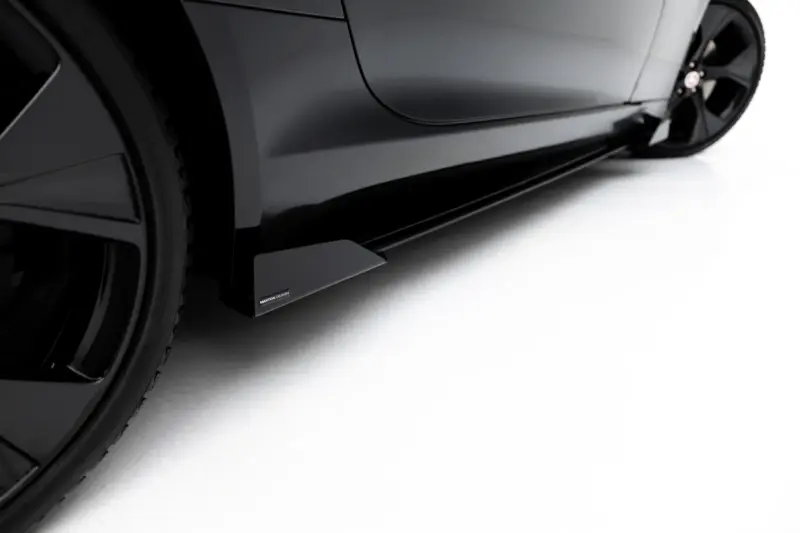 Close-up of a black car's lower side panel with a Maxton Design rocker accessory attached, wheel visible on the left.