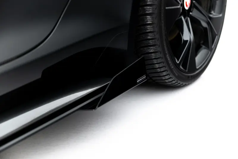 Close-up of a black car's wheel and side panel, highlighting the tire and Maxton Design badge on the side skirt.